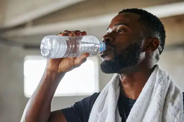 Hydration: The Secret Ingredient for a Toned Stomach and Enhanced Fitness 1 Image of man drinking water to improve hydration Newbury after work out.